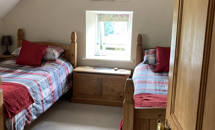 A twin room with a wash basin within Moorland, and a private toilet and over the bath shower off the landing. Window over looking the garden at Llwyn